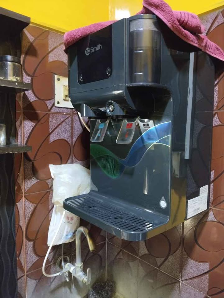 AO Smith Z9 Pro RO water purifier front close-up view showing transparent water storage tank with visible water level and child lock on hot water dispenser tap marked as red